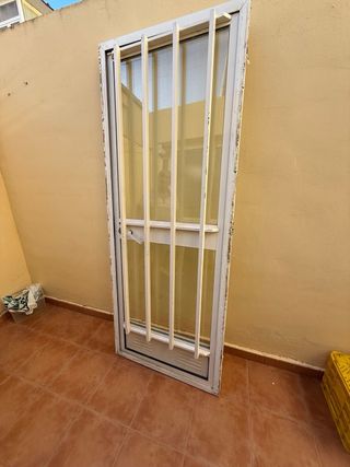 Puerta de aluminio con rejas y cristal