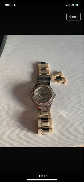 Reloj Guess con brillantes plateado y beige.