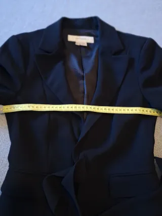 Elegante chaqueta negra con lazada. Fondo armario.