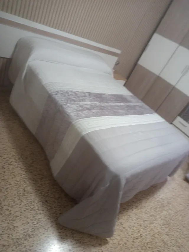 Colcha Cama Gris y Blanca y lleva una tira de bril