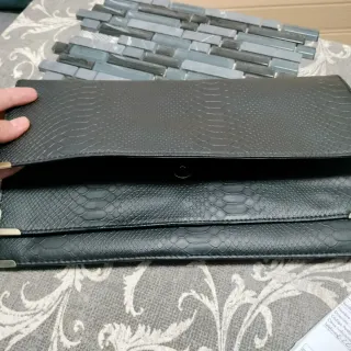 Cartera de mano negra con detalles dorados