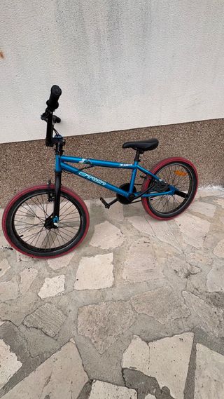 Bicicleta BMX azul con ruedas rojas