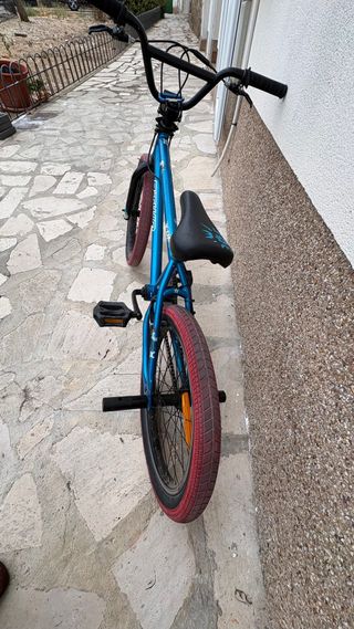 Bicicleta BMX azul con ruedas rojas