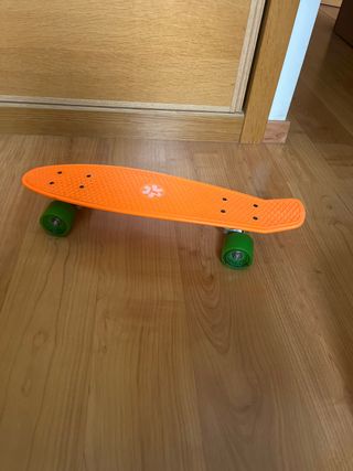 Monopatín naranja con ruedas verdes