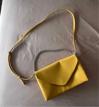 Bolso sobre amarillo con cadena plateada