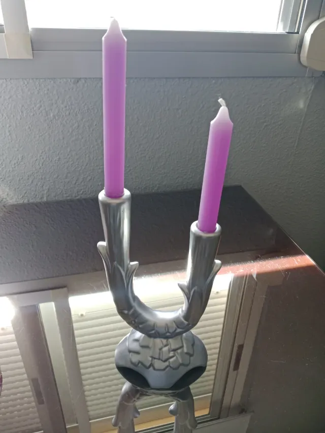 Candelabro de metal plateado con velas moradas