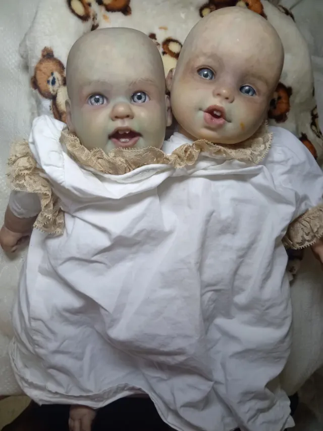 Bambole siamesi modificate con chiodi