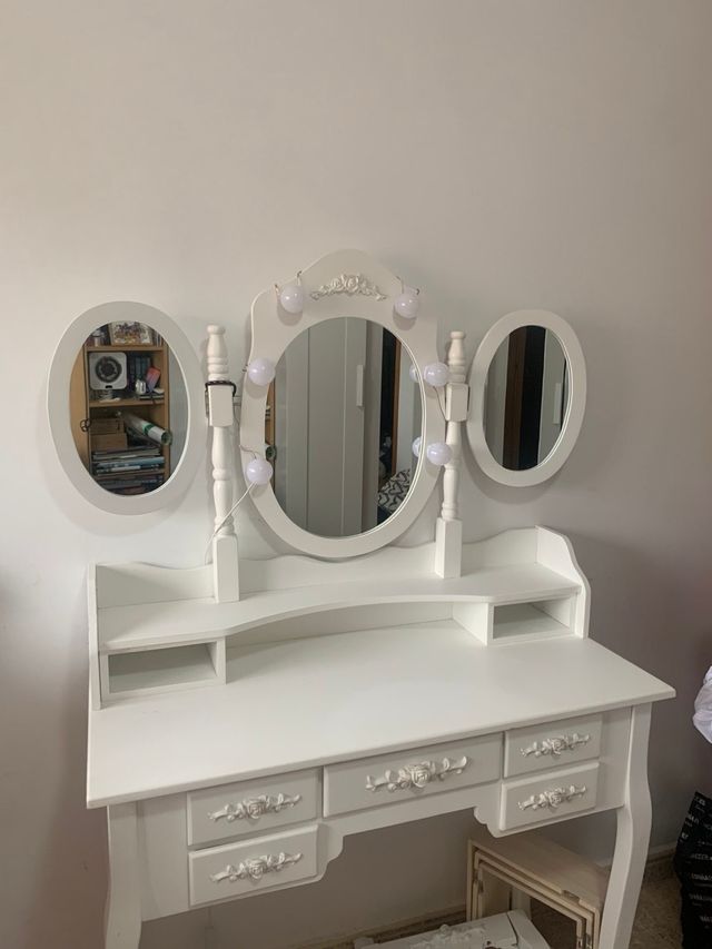 Tocador blanco con espejo, luces y taburete.
