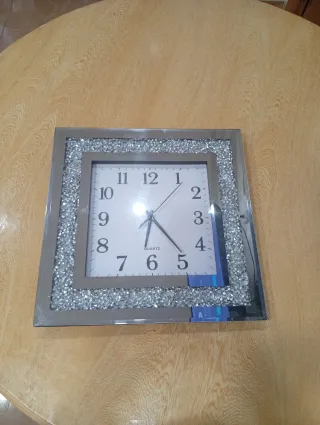 Reloj de pared plateado con pedrería