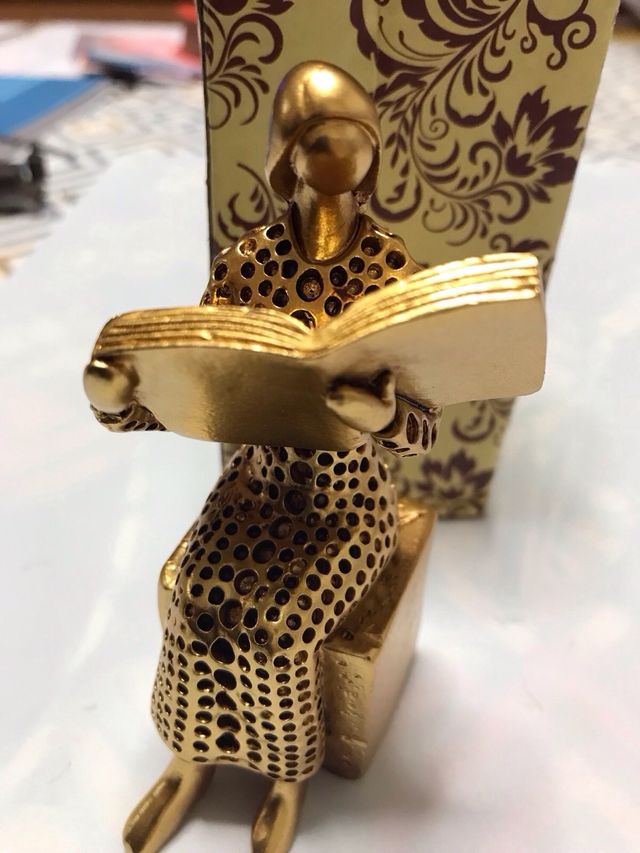 Figura dorada de mujer leyendo