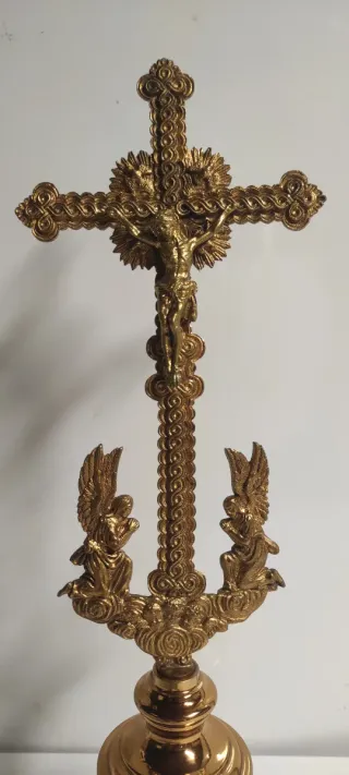 Crucifijo de latón con ángeles y base verde.