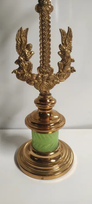 Crucifijo de latón con ángeles y base verde.