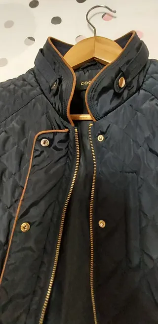 Chaqueta acolchada azul oscuro con ribetes marrón.