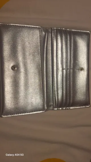 Cartera de mano plateada con diseño G