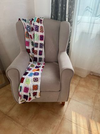 Sillón de tela beige con manta multicolor