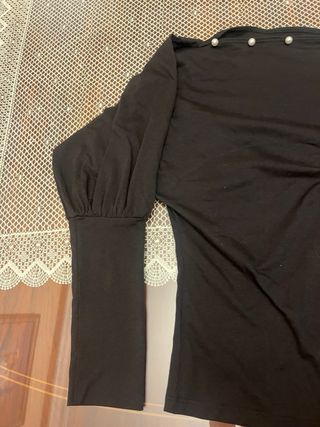 Camiseta negra con perlas y hombros descubiertos