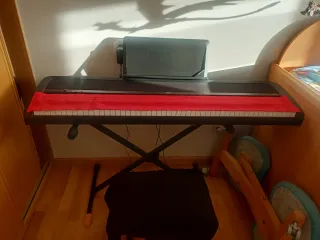 Teclado digital negro con soporte, marca Korg.