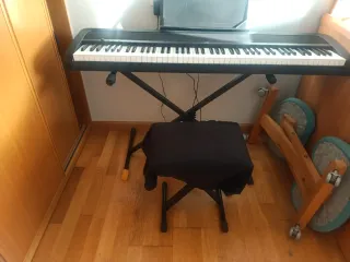Teclado digital negro con soporte, marca Korg.
