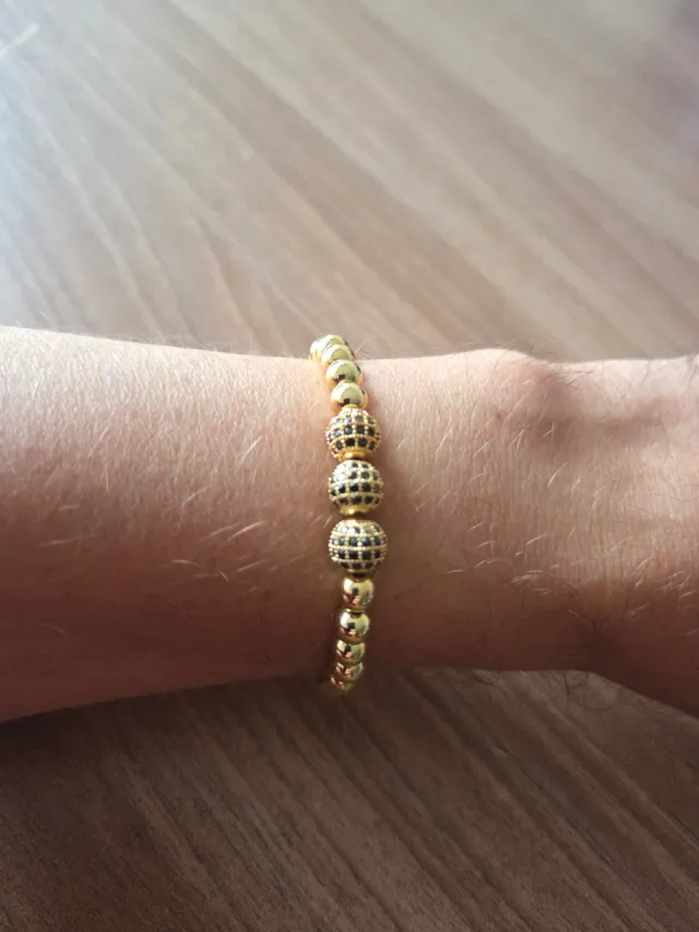 Pulsera dorada con detalles negros