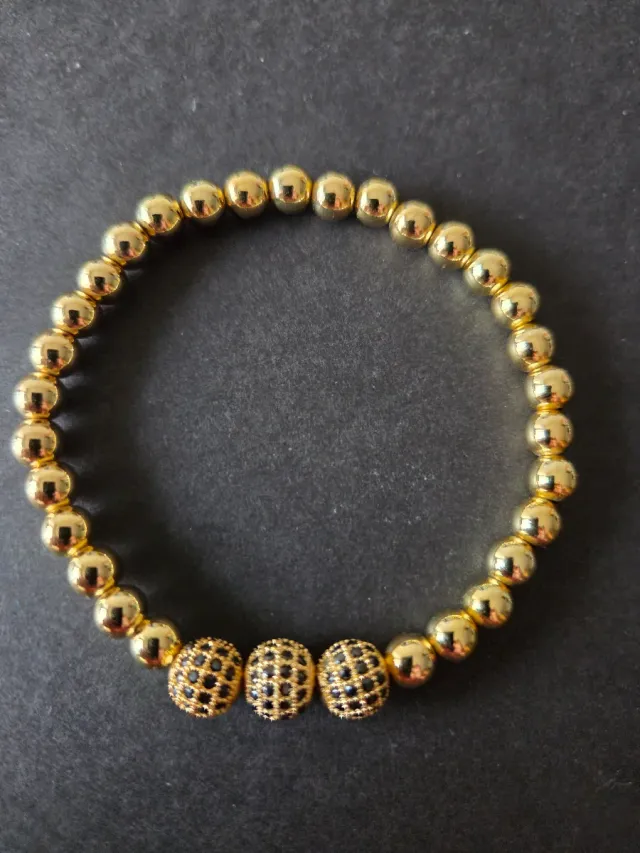 Pulsera dorada con detalles negros