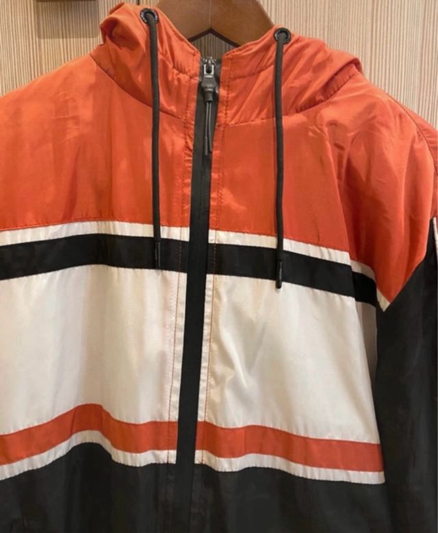 Abrigo cortavientos con capucha naranja y negro