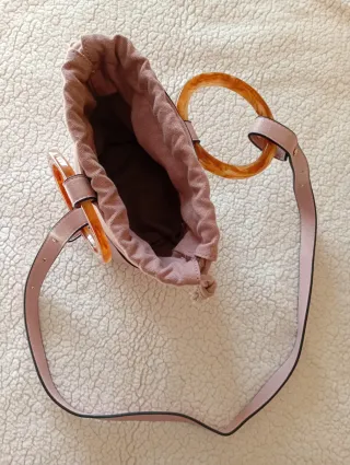 Bolso rosa con anillas y cinta para colgar.