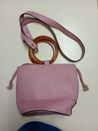 Bolso rosa con anillas y cinta para colgar.