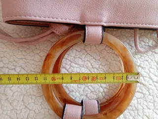 Bolso rosa con anillas y cinta para colgar.
