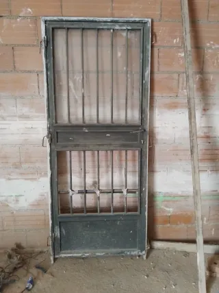 Puerta metálica con rejas y cristal