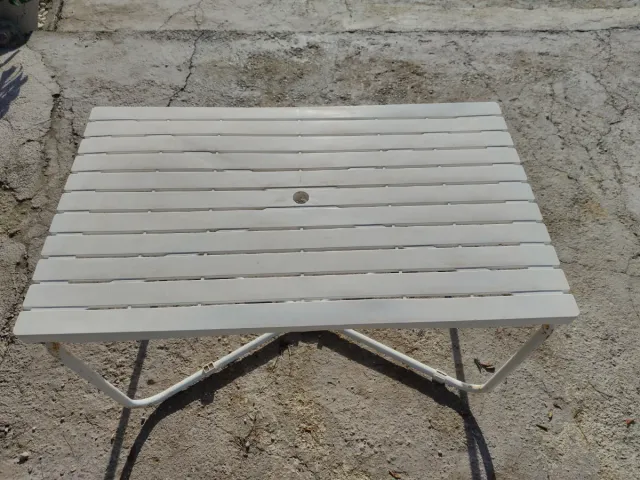 Mesa de jardín blanca con hueco para sombrilla.