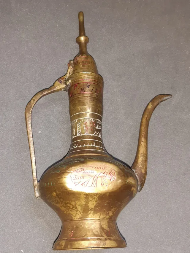 Jarra de metal dorada con detalles rojos