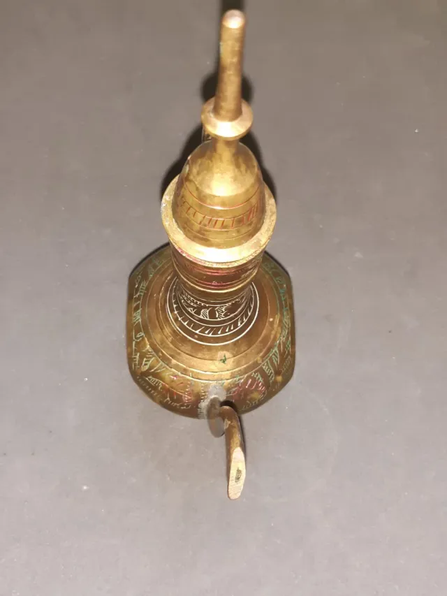 Jarra de metal dorada con detalles rojos