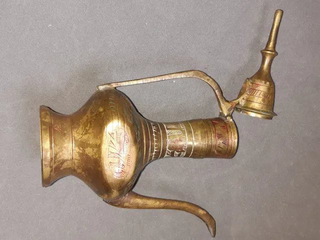 Jarra de metal dorada con detalles rojos