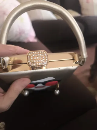 Bolso rígido dorado cara mujer gafas rojas