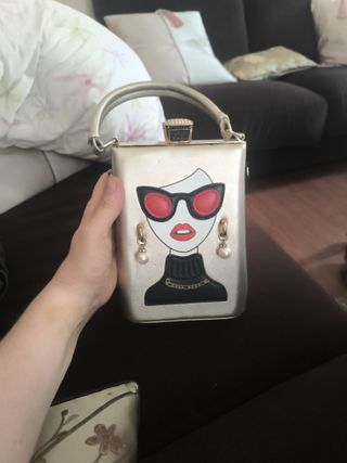 Bolso rígido dorado cara mujer gafas rojas
