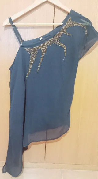 Blusa asimétrica con abalorios dorados.
