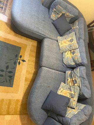 Sofá modular azul con cojines y alfombra a juego. 