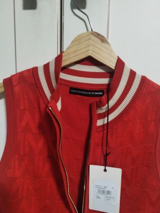 Chaleco de punto rojo con cremallera dorada.