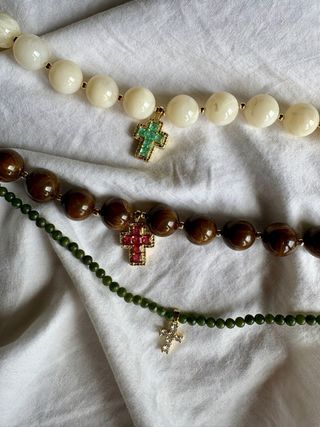 Collar marrón con cruz dorada y piedras rosas