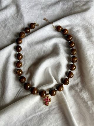 Collar marrón con cruz dorada y piedras rosas