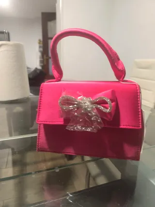 Bolso de mano rosa con lazo brillante