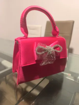 Bolso de mano rosa con lazo brillante
