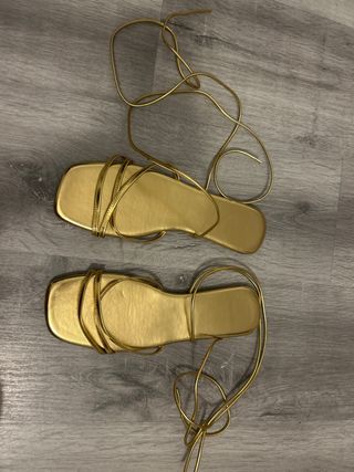 Sandalias doradas atadas al tobillo