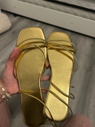 Sandalias doradas atadas al tobillo