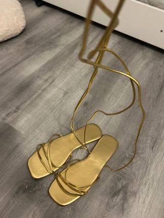 Sandalias doradas atadas al tobillo