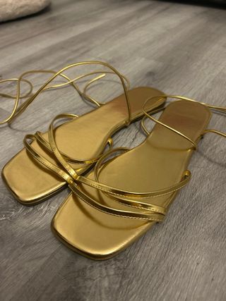 Sandalias doradas atadas al tobillo