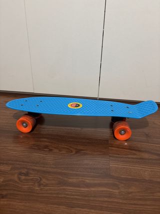 Monopatín azul con ruedas naranjas