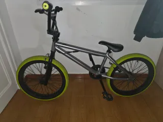 Bicicleta BMX plateada con ruedas verdes
