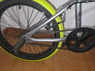 Bicicleta BMX plateada con ruedas verdes