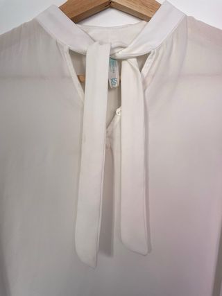 Blusa blanca semitransparente con lazo en cuello